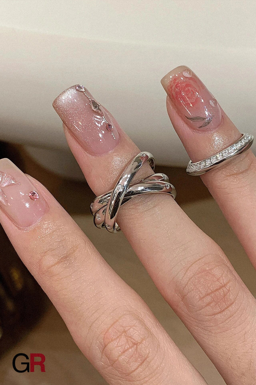 “GlamoROZ Éclat Entrelacé Silver Multi-Layer Trinity Ring Jewelry flat-lay on soft beige fabric background”