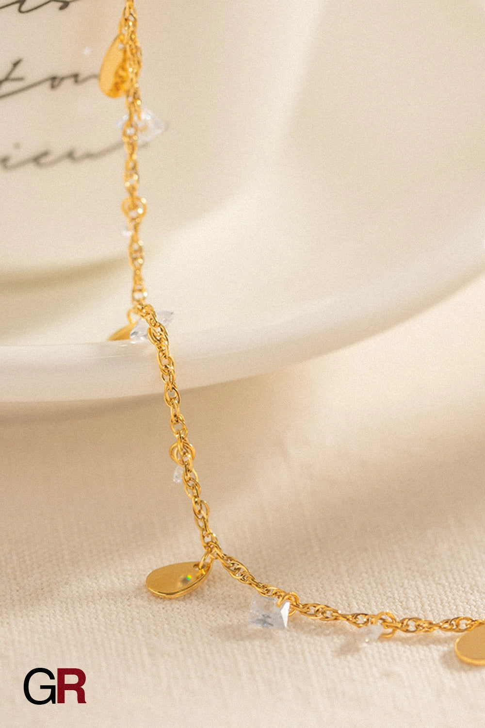 “GlamoROZ Éclat Doré Luminous Tassel Anklet gold droplet charm and chain detail close-up”