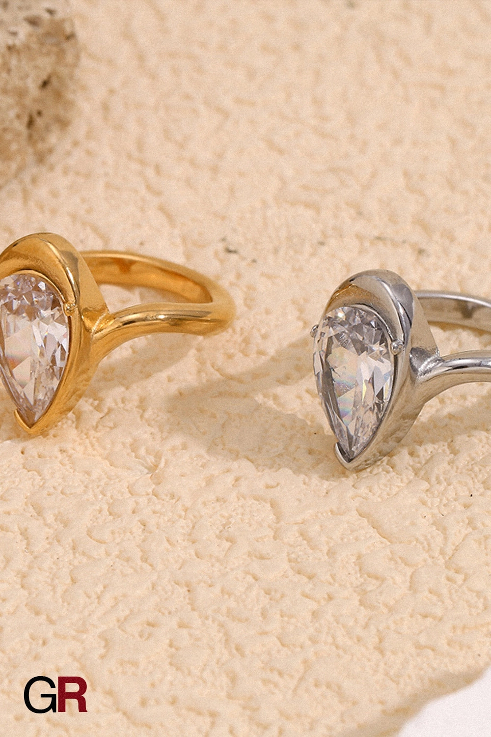 “GlamoROZ Aureole Doré Teardrop Open Band Ring Jewelry flat-lay on soft beige fabric background”